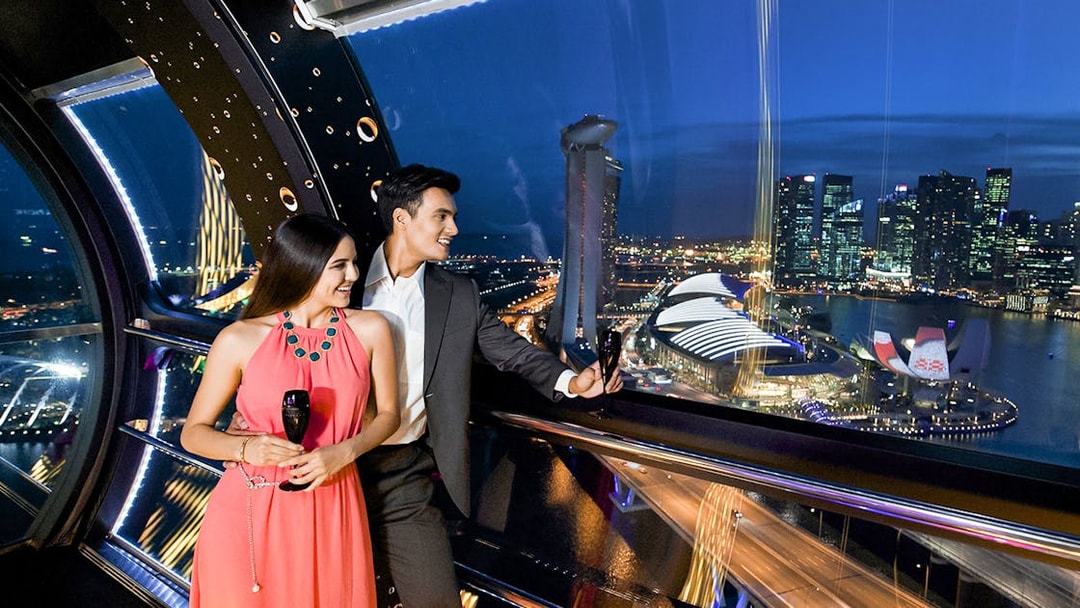 Couple enjoying champagne at 165 Sky Dining, Singapore Flyer with city skyline view.