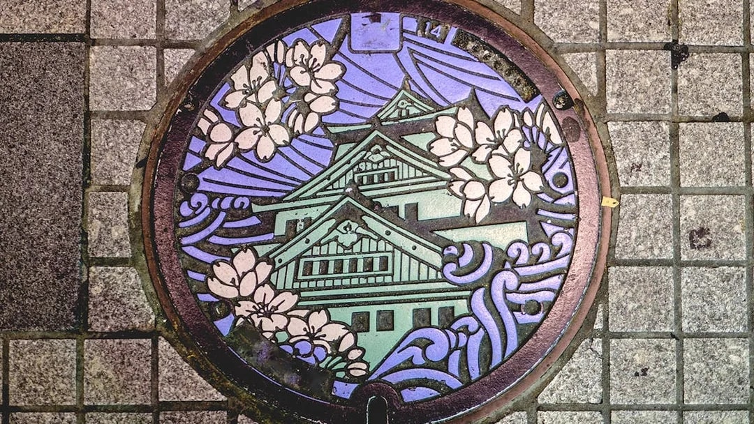 Decorative manhole cover featuring Osaka Castle and cherry blossoms in Osaka Namba.