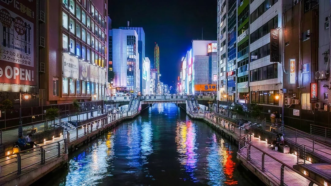 Neon-lit canal and vibrant signboards in Dotonbori, Osaka at night.