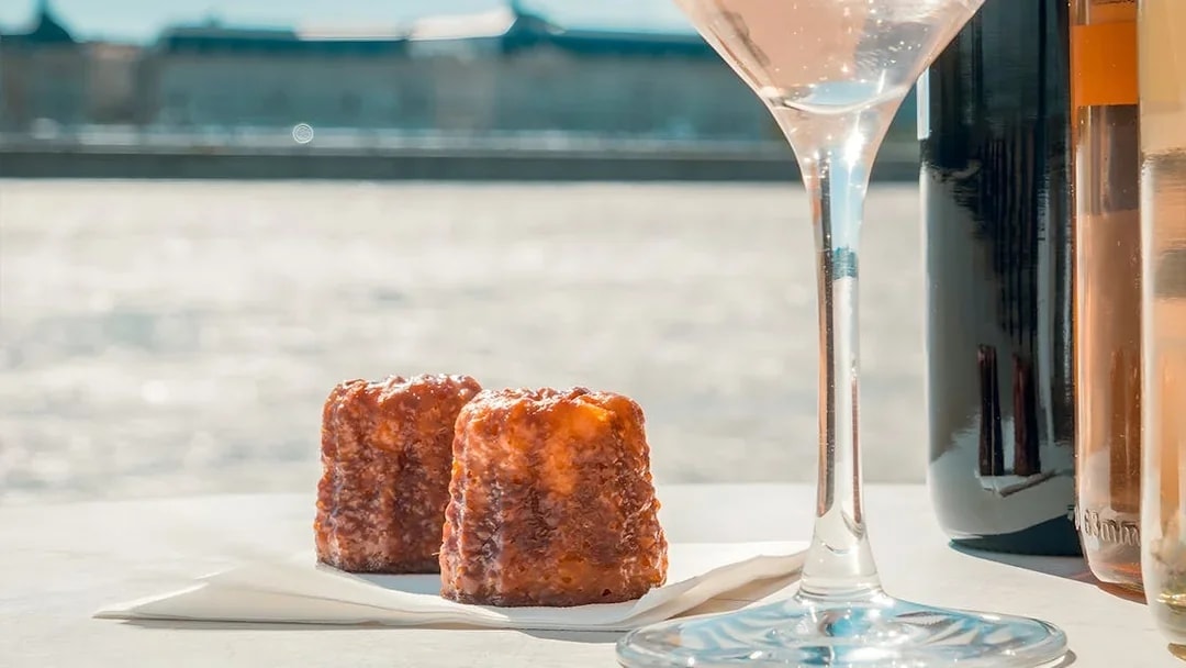 Canelés and wine glass on Bordeaux River Cruise table.