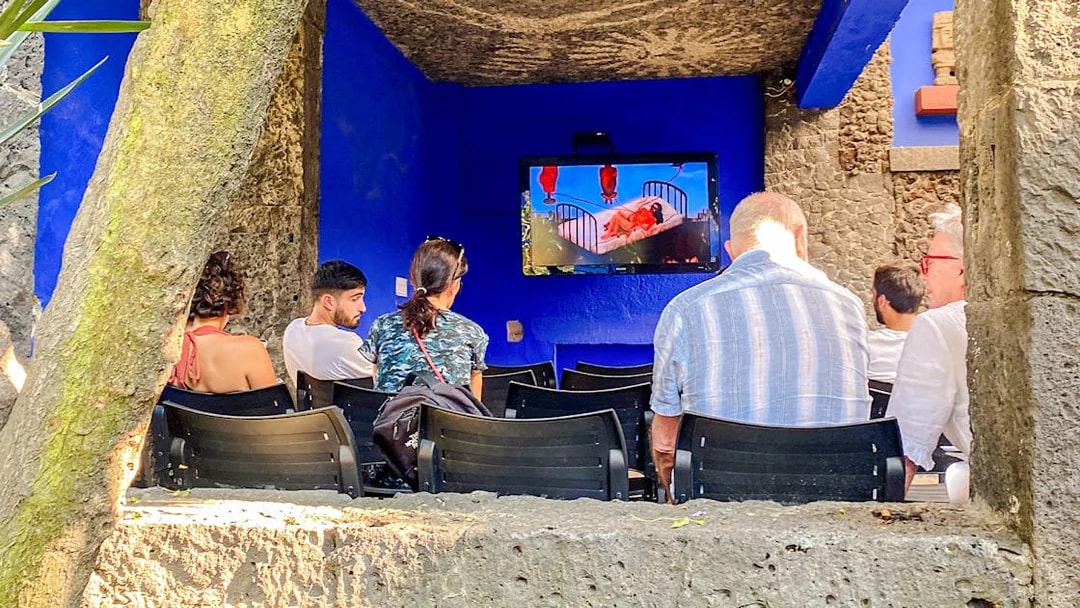 Visitors watching a video at the Frida Kahlo Museum's outdoor area.