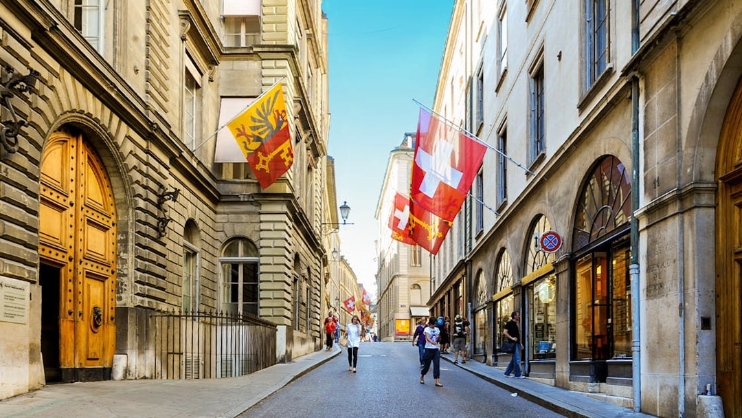 Street view in Geneva with Swiss and city flags, part of a 2-hour guided tour.