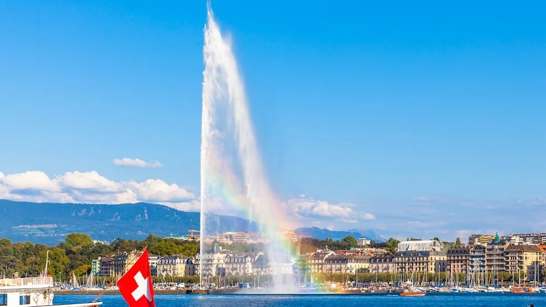 Jet d'Eau fountain in Geneva with Swiss flag boat on Lake Geneva.