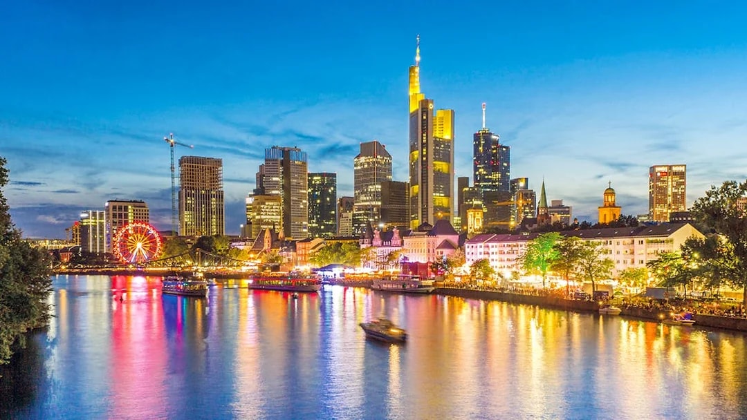 Frankfurt skyline at dusk with illuminated buildings and river during Evening Panorama Cruise.