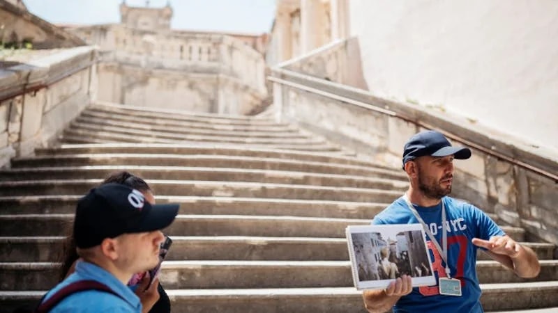Tour guide showing Game of Thrones filming location on stone steps in Dubrovnik.