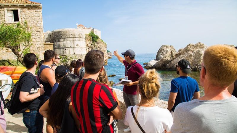 Tour group in Dubrovnik exploring Game of Thrones filming locations by the sea.