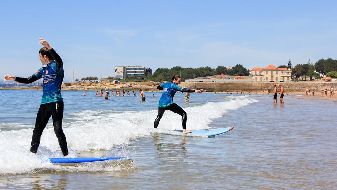 Surfers balancing on boards during a group lesson in Lisbon.