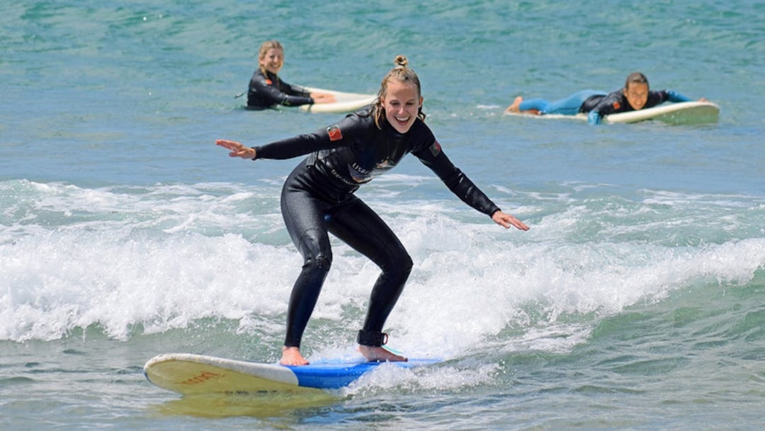 Group surf lesson participants riding waves in Lisbon.