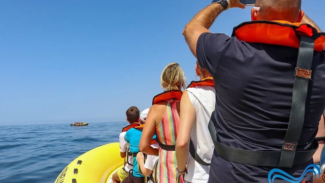 Tourists on a boat wearing life jackets, heading towards Benagil Caves for dolphin discovery.