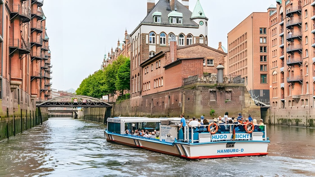 Harbor cruise boat navigating through Hamburg's Speicherstadt district canal.