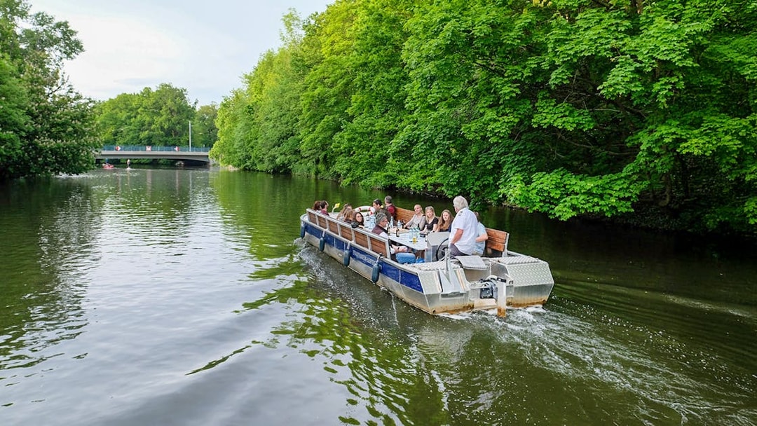 Guests on a motorboat tour along Karl Heine Canal, Leipzig, surrounded by lush greenery.