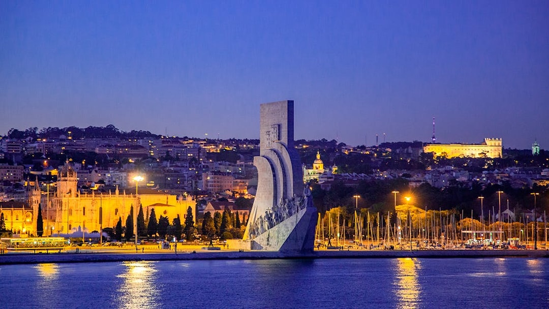 Lisbon night view with Monument to the Discoveries and illuminated cityscape.