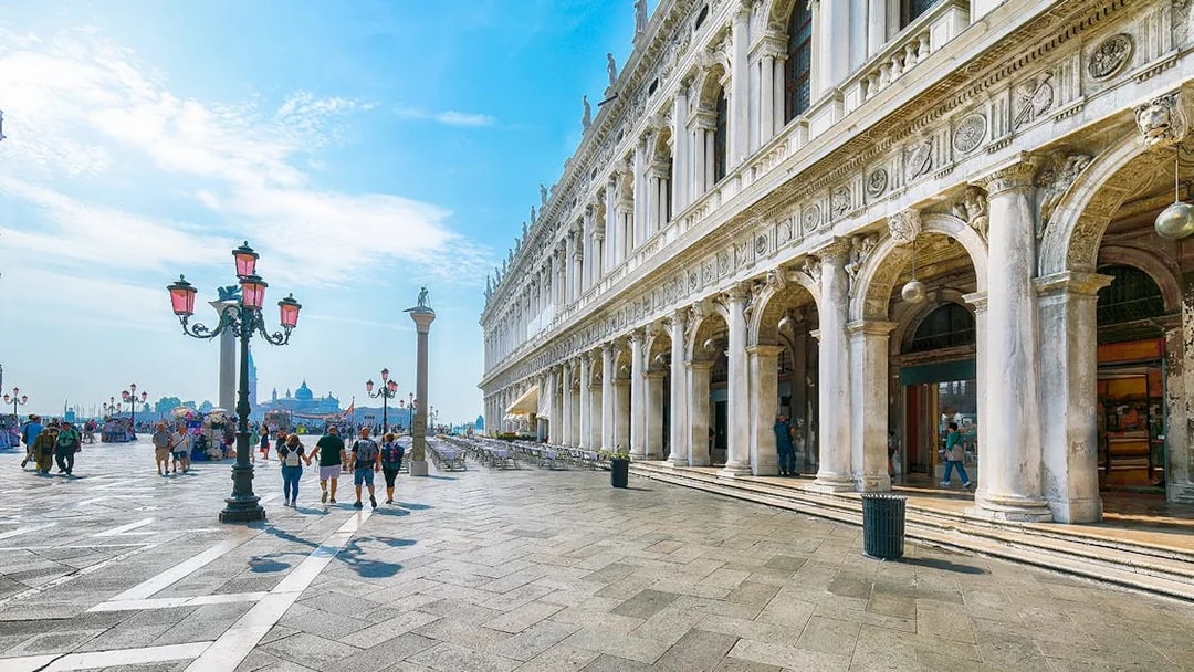 San Marco square in Venice with historic architecture and people walking.
