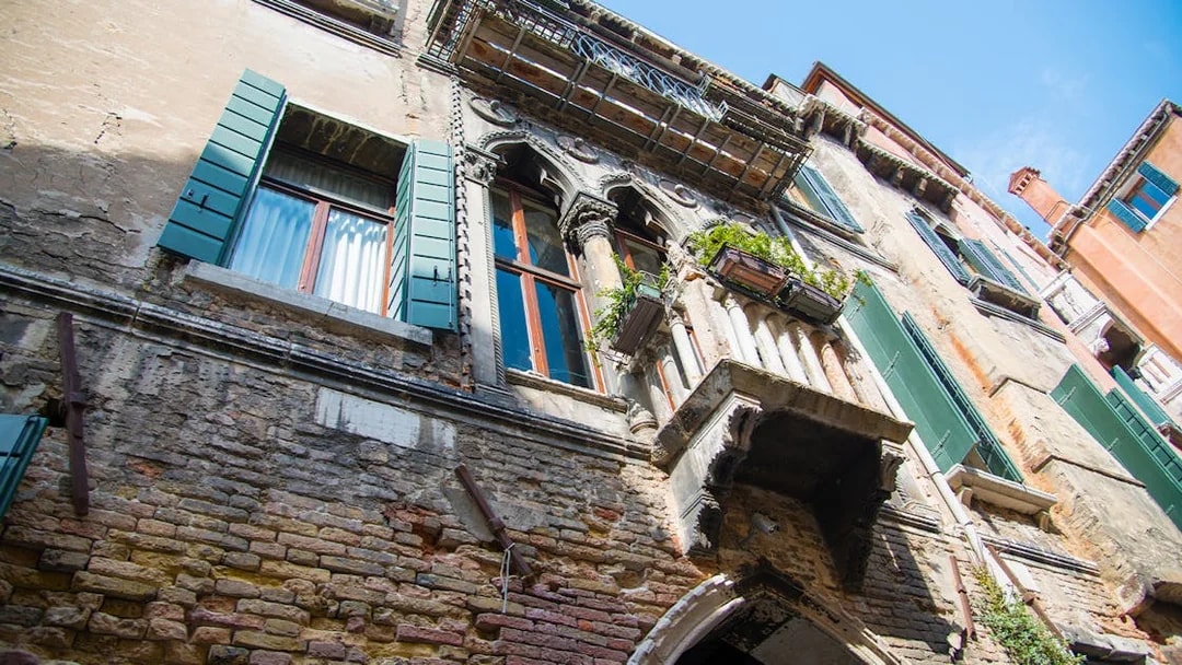 Venetian architecture with green shutters and ornate balcony on a historic building in Venice.