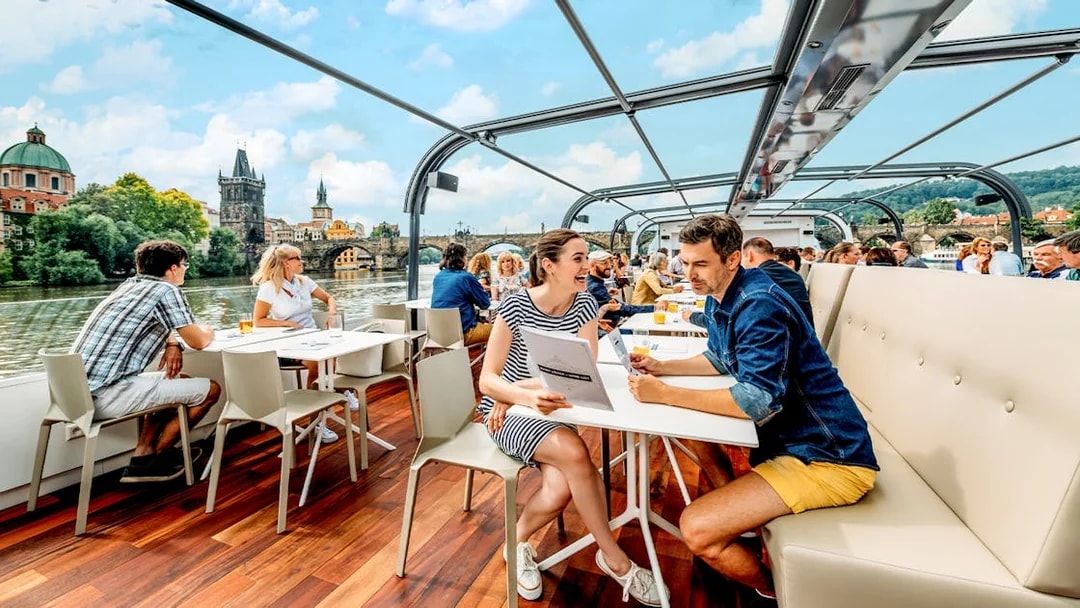 Vltava River cruise with passengers enjoying views of Prague landmarks.