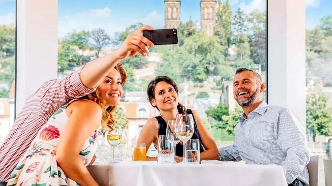 Group taking a selfie on Vltava River cruise with Prague skyline in background.