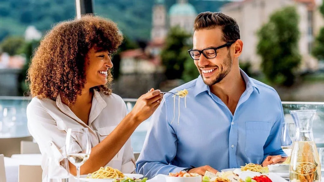 Couple enjoying lunch on Vltava River sightseeing cruise in Prague.