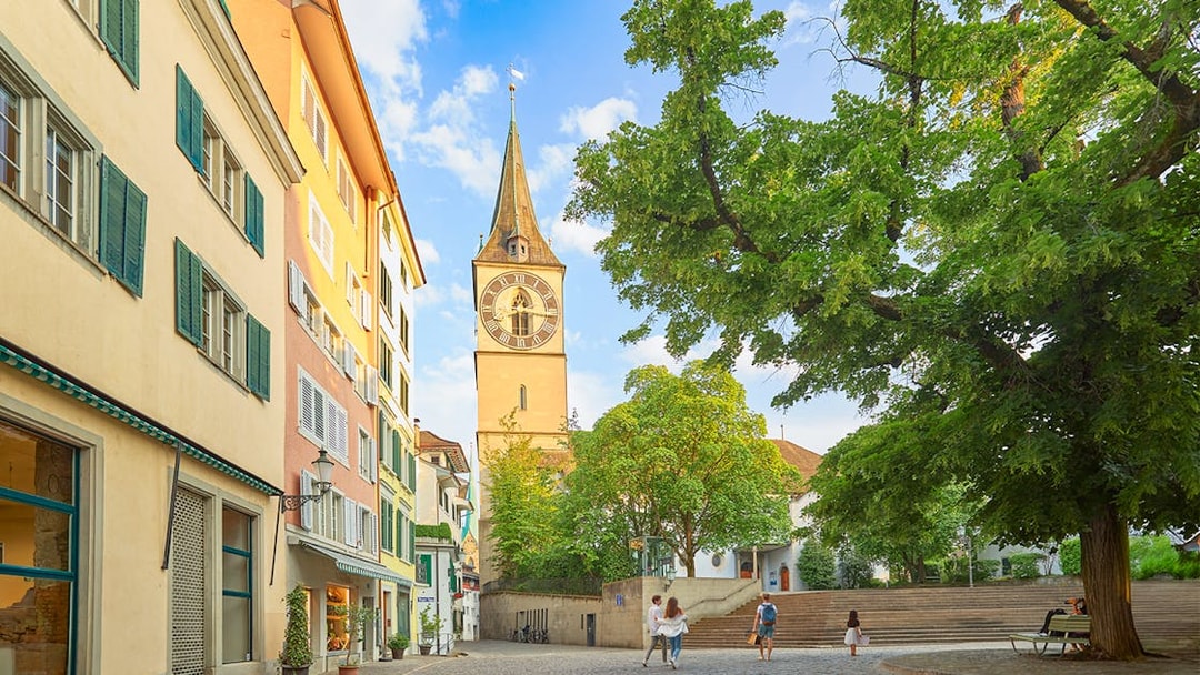 Zürich city square with St. Peter's Church tower and colorful buildings.