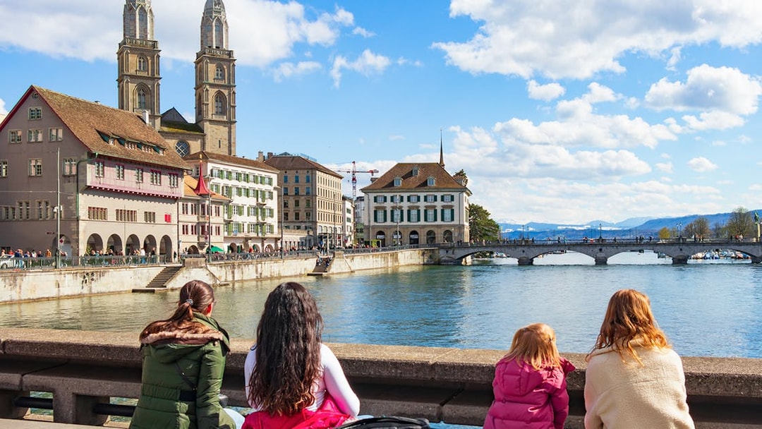People enjoying the view of Grossmünster and Limmat River on Zürich city tour.