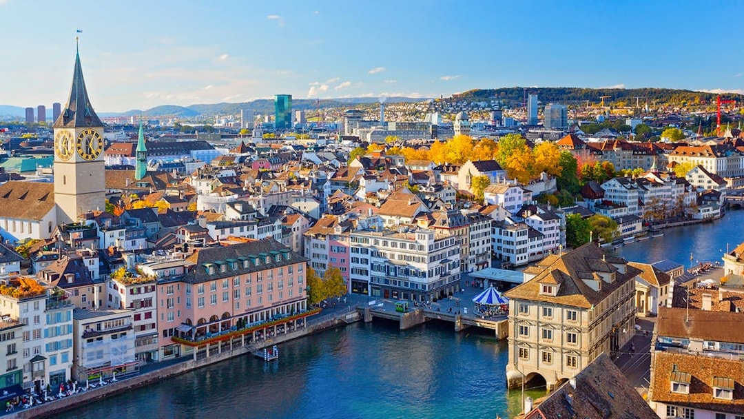 Zurich cityscape with Limmat River and historic buildings under a clear blue sky.