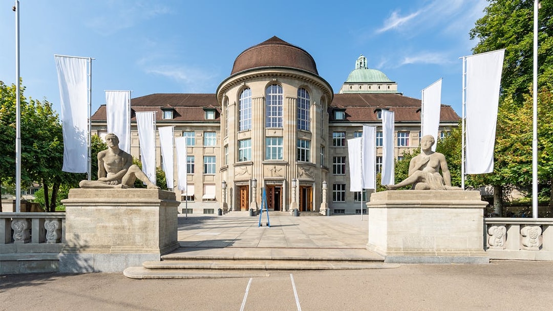 Zürich University main building with statues and flags on the Best of Zürich City Tour.