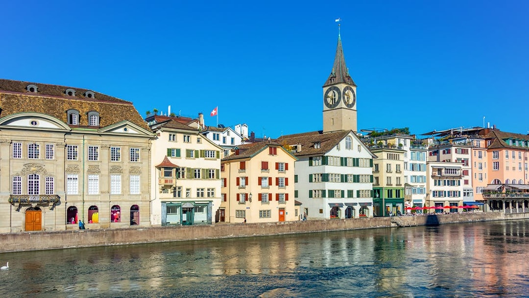 Historic buildings along the Limmat River with St. Peter's Church in Zürich.