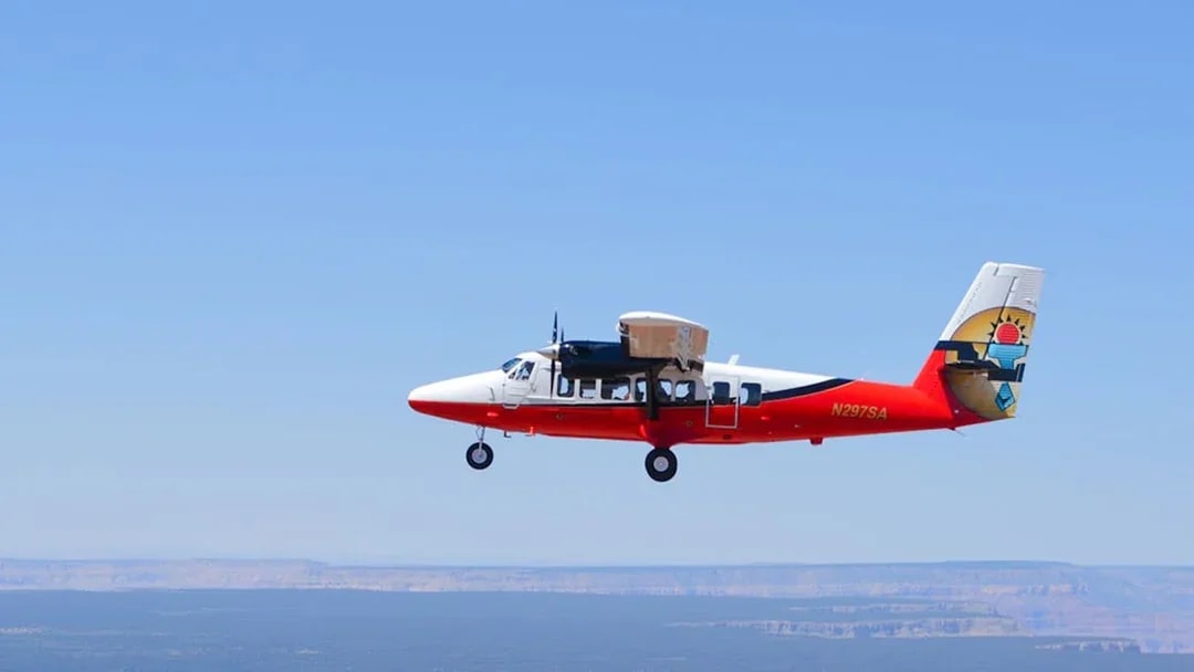 Airplane flying over Grand Canyon West with clear blue sky.