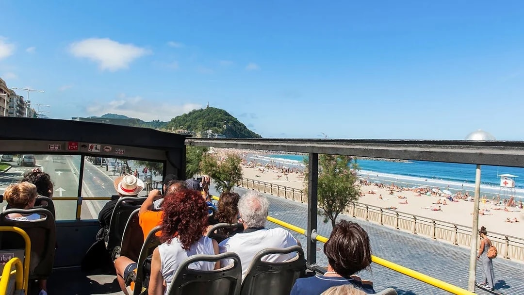 Open-top bus tour along La Concha Beach in San Sebastian, Spain.