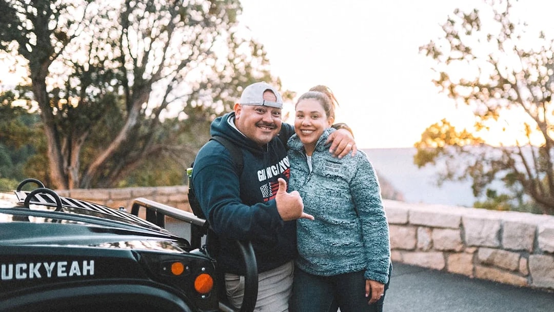 Tourists posing by a jeep on a Grand Canyon guided tour.