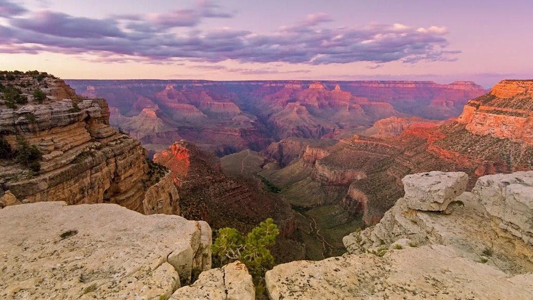 Grand Canyon at sunset with layered rock formations and expansive canyon view.
