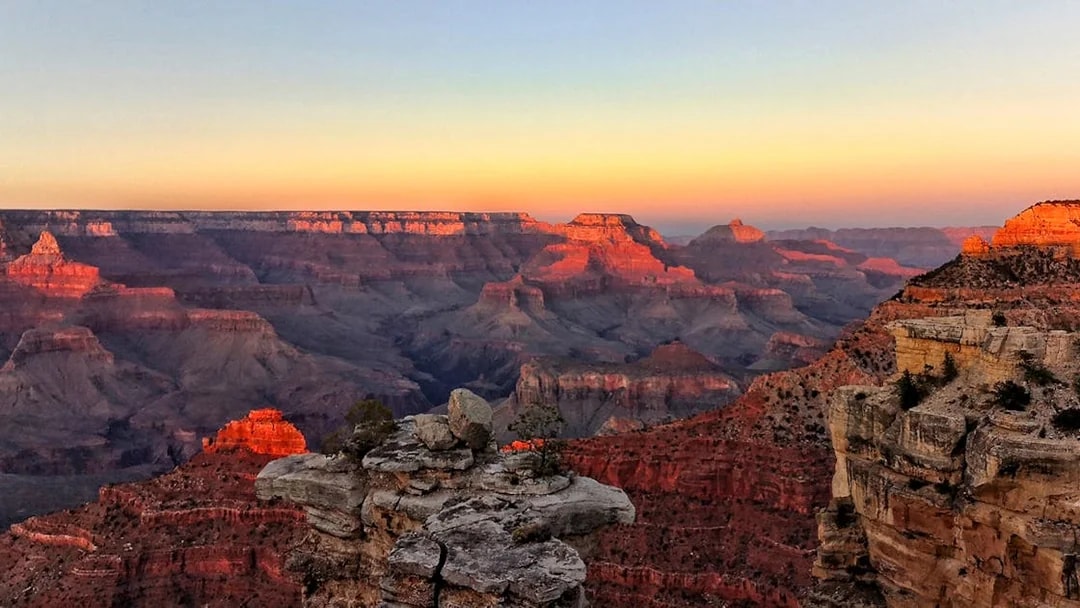Grand Canyon at sunset with layered rock formations and vibrant colors.