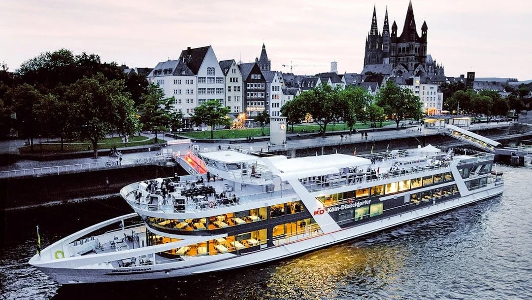 Evening cruise ship on the Rhine River with Cologne Cathedral in the background.