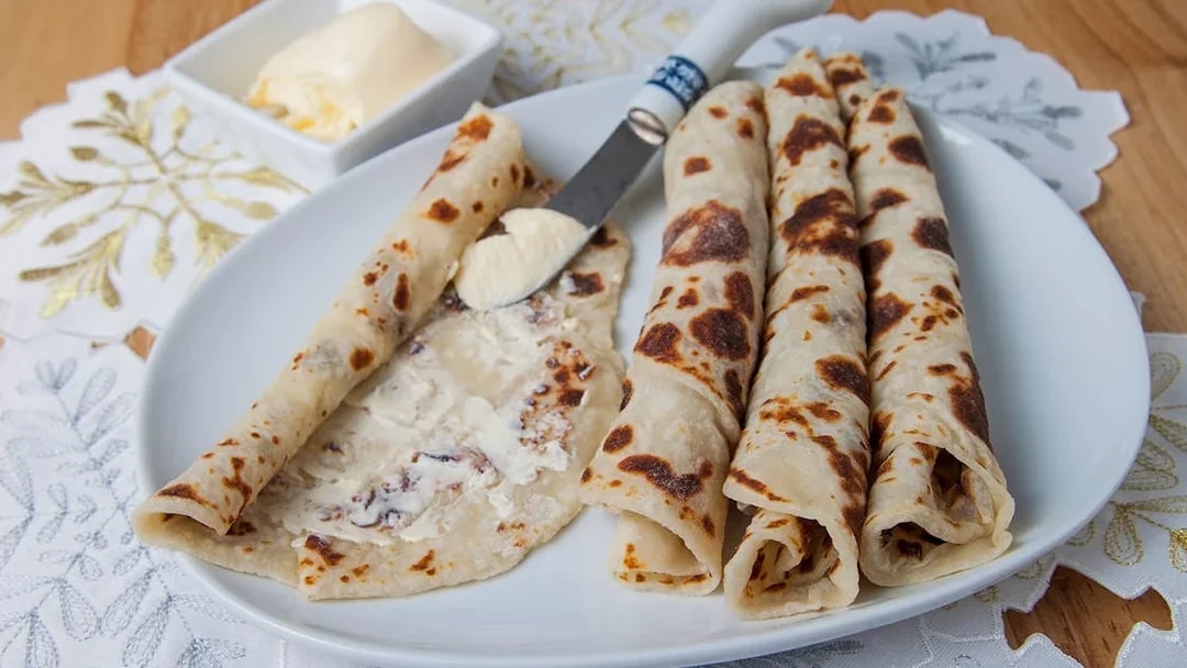 Norwegian lefse with butter on a plate, traditional snack for Aurora borealis tour.