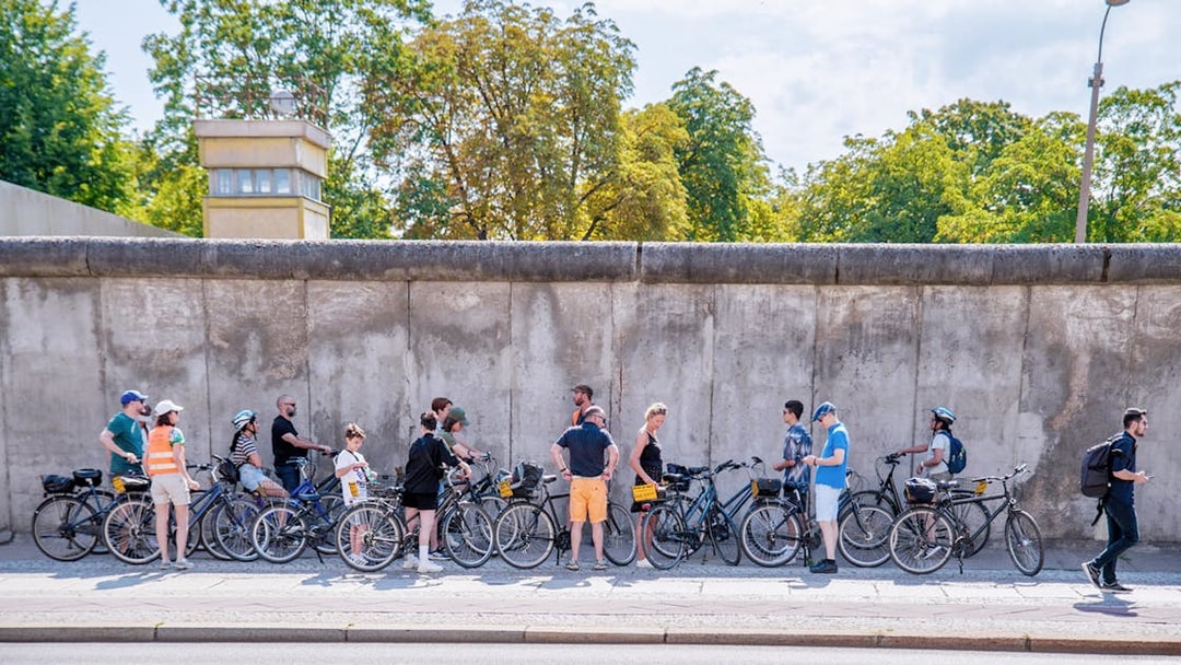 Cyclists on a guided tour stop at the Berlin Wall, Berlin.