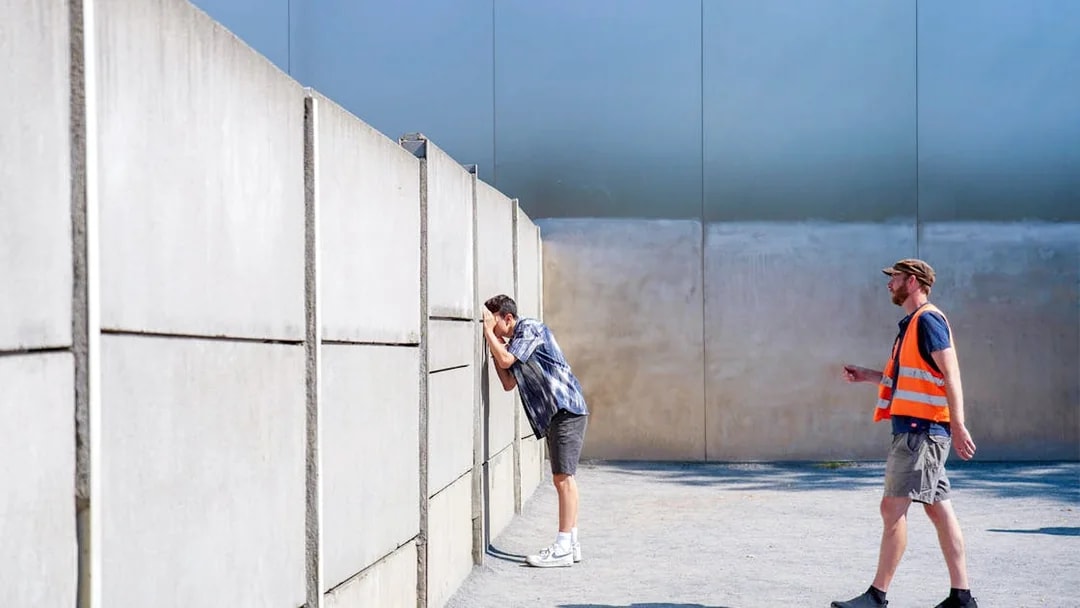 Man looking through Berlin Wall with guide during bike tour.