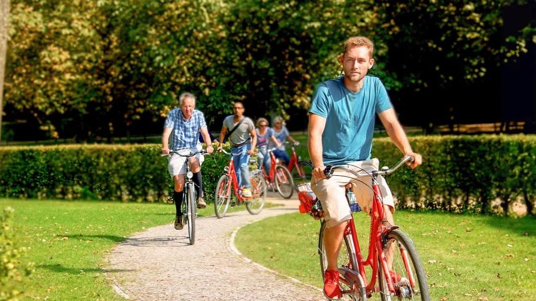 Cyclists on a guided tour ride along a park path in Germany.