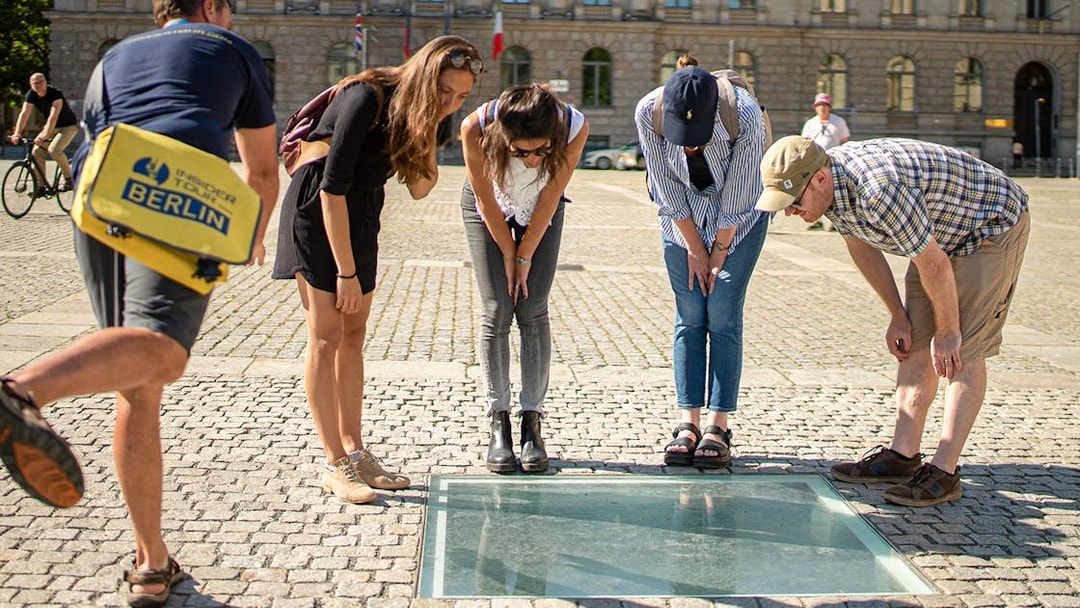 Visitors observing the Bebelplatz memorial during a 3-hour guided tour of Berlin.