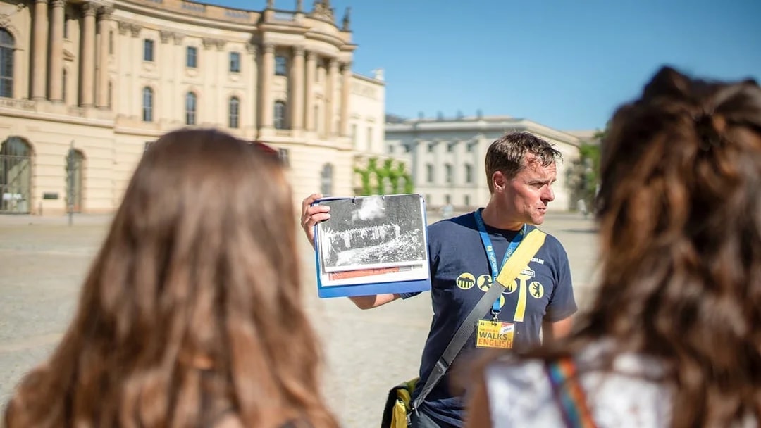 Tour guide showing historical photo during Berlin tour.