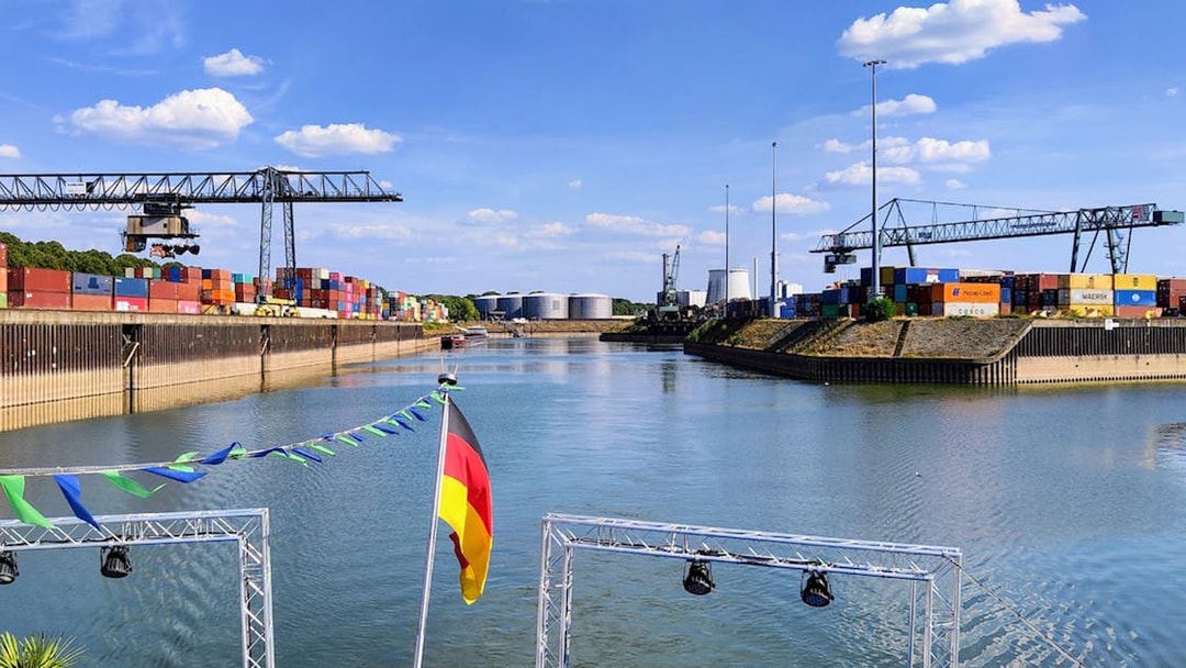 Cologne Harbour with cranes and shipping containers along the waterway.