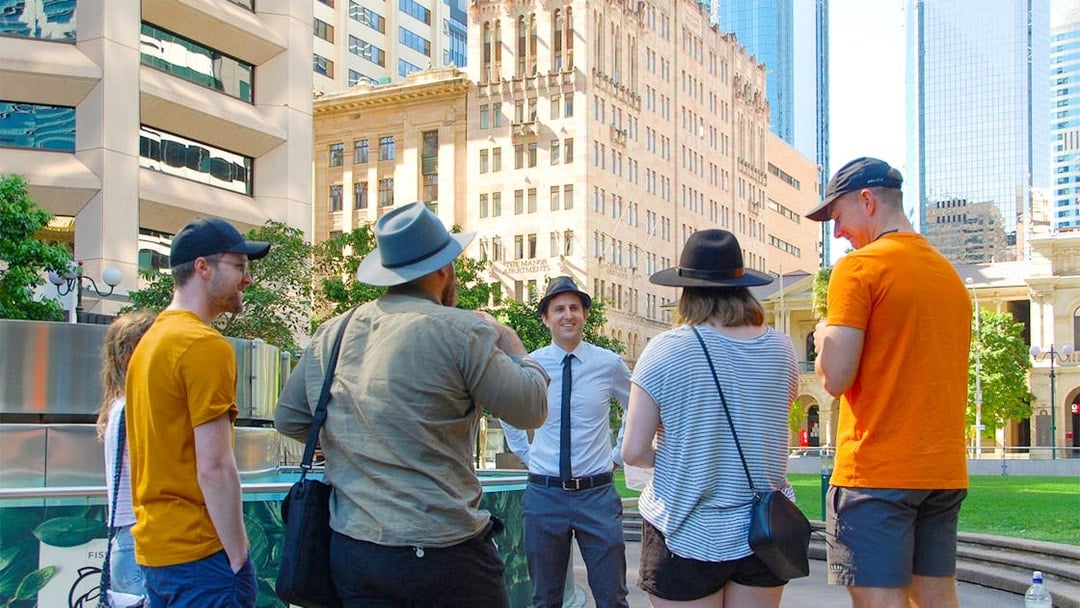 Group on a walking tour in Brisbane city center with historic buildings in the background.