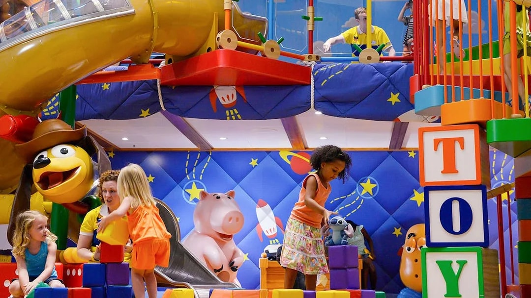 Kids playing in a Disney-themed club with colorful toys and slides on a Disney Adventure Cruise.