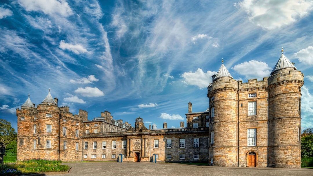 Palace of Holyroodhouse in Edinburgh with blue sky and clouds.