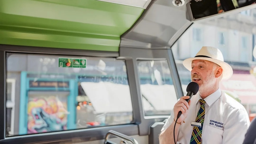 Guide speaking into a microphone on an Edinburgh HOHO bus tour.