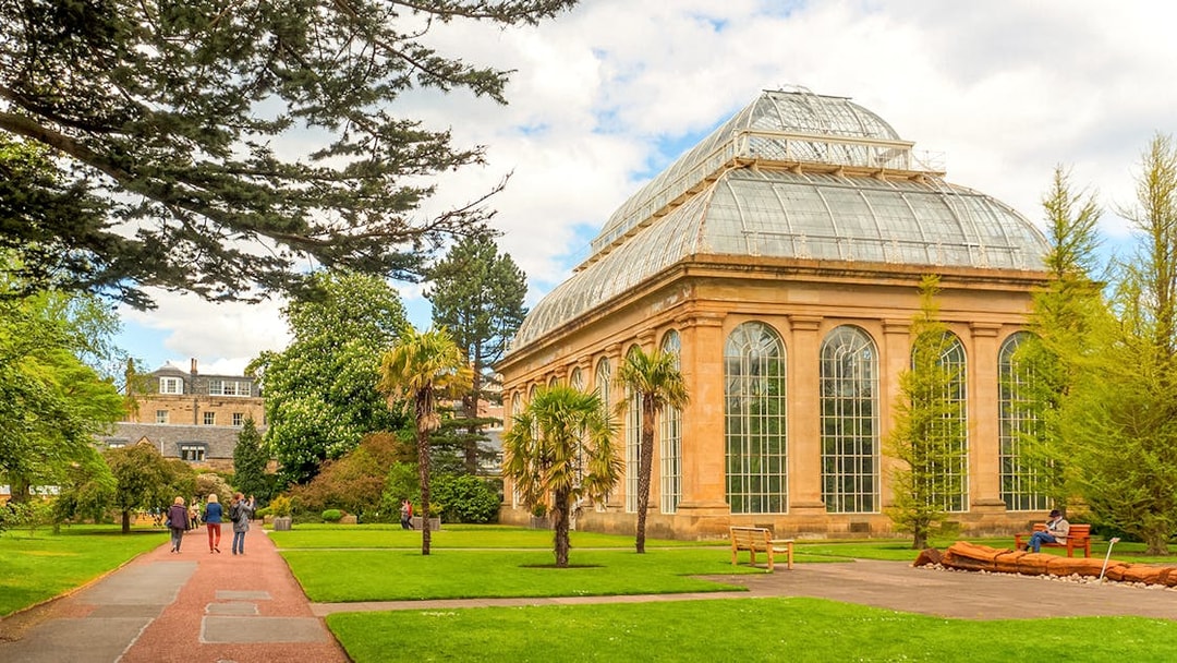 Edinburgh Botanic Garden glasshouse with visitors walking nearby.