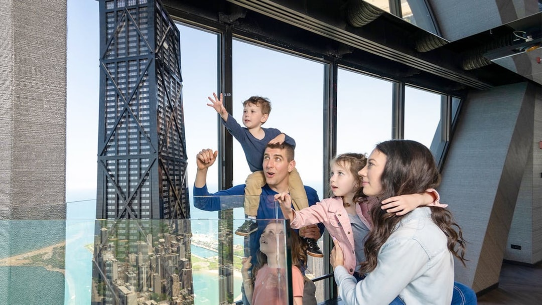 Family enjoying view from Chicago 360 Observation Deck with city skyline.