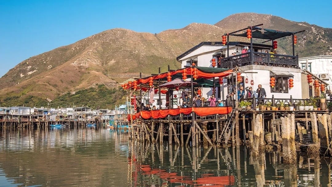 Stilt houses with red lanterns in Tai O fishing village, Hong Kong, viewed from the water.