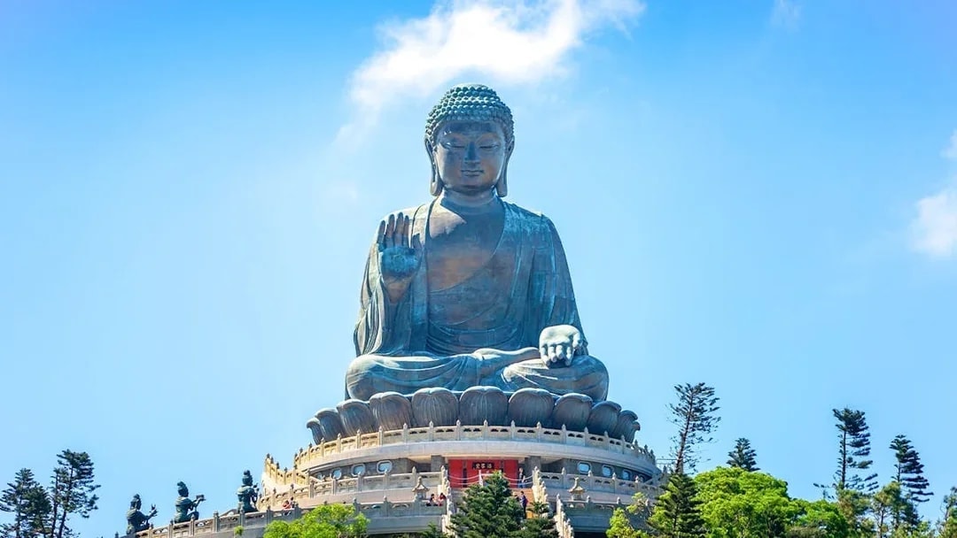 Tian Tan Buddha statue on Lantau Island, Hong Kong, viewed from below with surrounding trees.