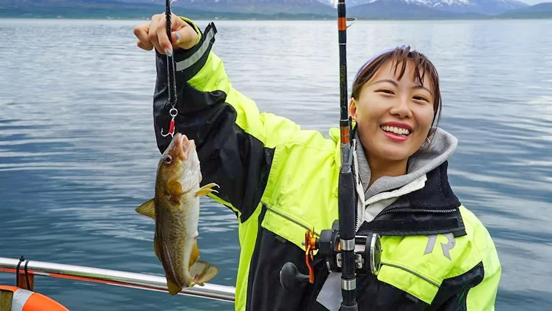 Fishing on a cruise with a catch in hand, scenic ocean backdrop.