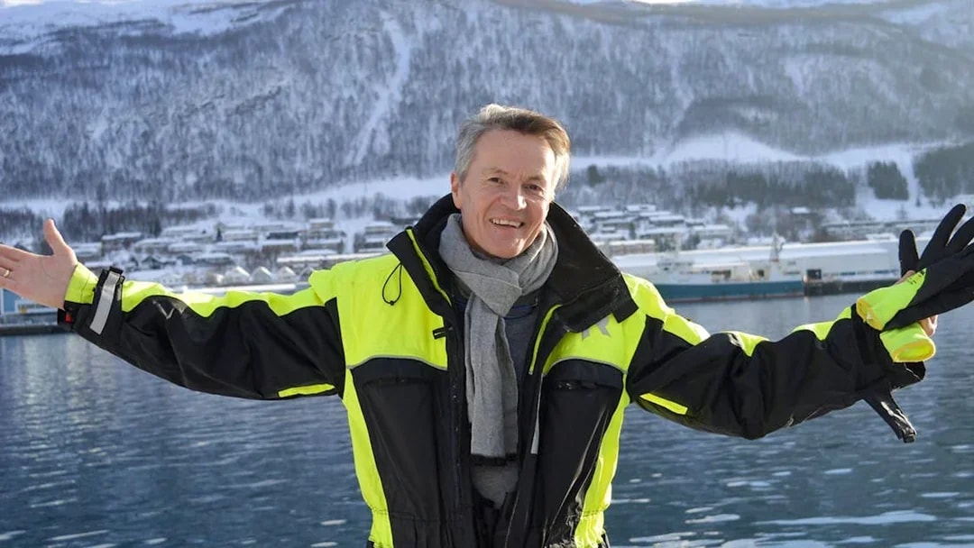 Guest in thermal suit on a cruise with snowy mountains in the background.