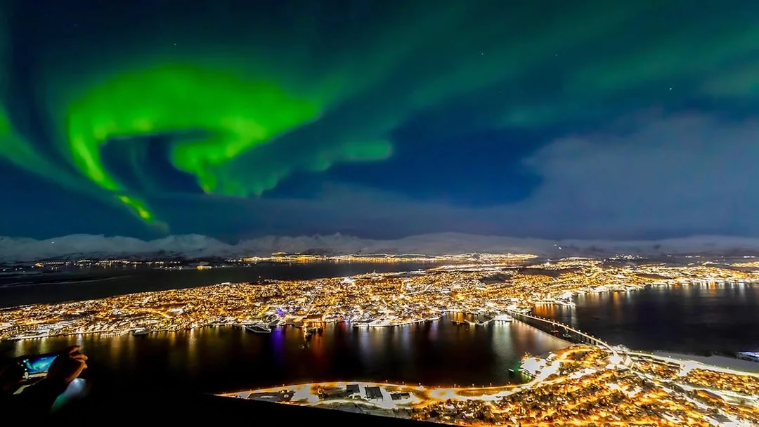 Northern lights over Tromso cityscape at night.